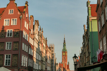 A close up of the facades of tall building in the middle of Old Town in Gdansk, Poland. The buildings have many bright colors, they are richly decorated. High tower of Town Hall. City tour. Clear day.