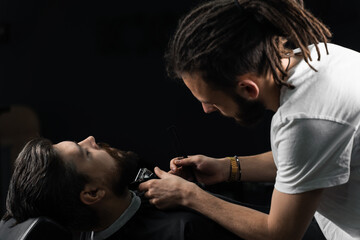 Obraz na płótnie Canvas Trimming the beard with a shaving machine. Advertising for barbershop and men's beauty salon