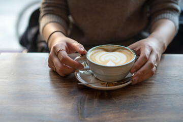 Fototapeta na wymiar holding a cafe latte with heart-shaped art.