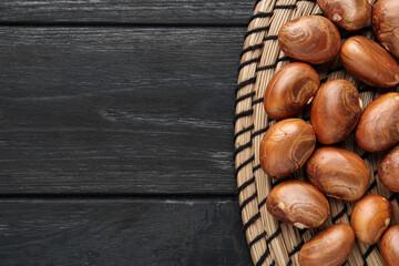 Raw jackfruit seeds on black wooden table, flat lay. Space for text