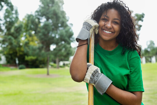 Portrait of beautiful young environmentalist holding rake in park