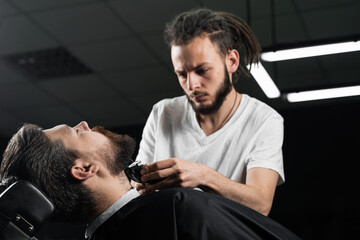 Trimming the beard with a shaving machine. Advertising for barbershop and men's beauty salon