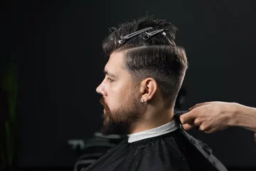 Fotobehang Low fade machine haircut for handsome bearded man in barbershop. Hair cut with a smooth transition. © Rabizo Anatolii