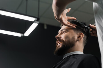 Low fade machine haircut for handsome bearded man in barbershop. Barber with dread locks making hairstyle with a smooth transition. - obrazy, fototapety, plakaty