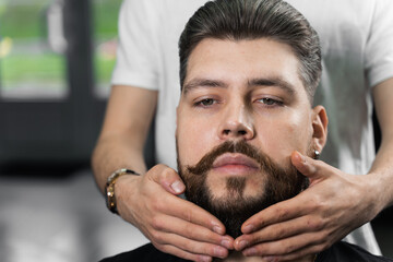 Fixing the shape of the beard with wax. The result of a haircut in a barbershop.