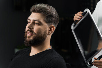Barber with dreadlocks showing result of low fade machine hair and beard cut for bearded man in...