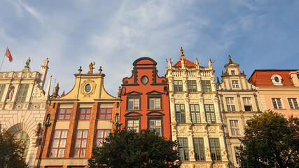 Fototapeta na wymiar A close up of the facades of tall building in the middle of Old Town in Gdansk, Poland. The buildings have many bright colors, they are richly decorated. City tour. Clear day.