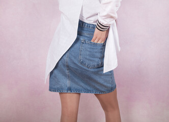 Young fashion woman, with jeans skirt, on pink background.
