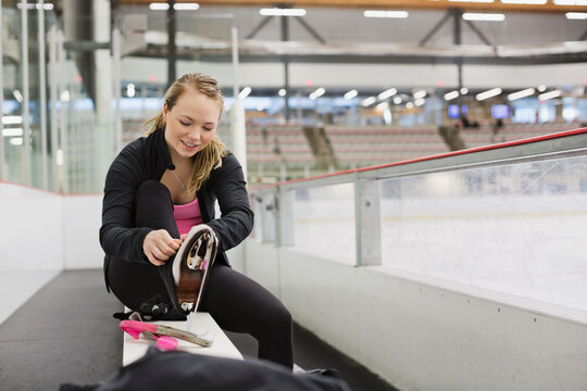 Female figure skater tying up skates in skating rink