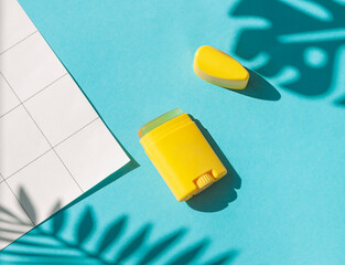 Sunscreen stick on the blue wet background with tropical leaves shadows. Summer vacation cosmetics concept. Top view - Powered by Adobe