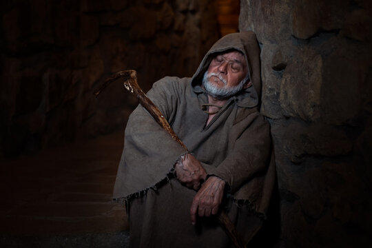 Old poor medieval beggar sleeps in alley