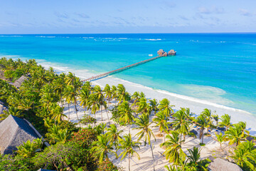Aerial shot of the Stilt hut with palm thatch roof washed with turquoise Indian ocean waves on the white sand sandbank beach on Zanzibar island, Tanzania.