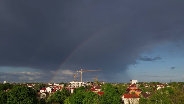 rainbow over a city residential area, beautiful cityscape after rain, aerial view of rainbow in the sky, houses and rooftops after rain with a rainbow