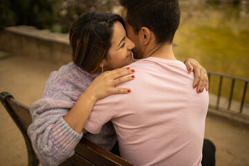 A couple in a romantic moment smiling and hugging in a park