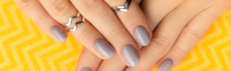 Beautiful groomed womans hands with trendy nail design on yellow background