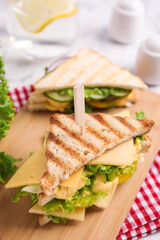Wooden board with tasty cheese sandwich on table