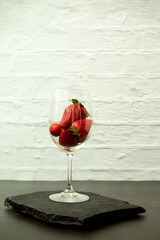 Ripe juicy red beautiful strawberry close-up is an appetizing fresh snack in a wine glass
