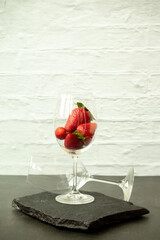 Ripe juicy red beautiful strawberry close-up is an appetizing fresh snack in a wine glass