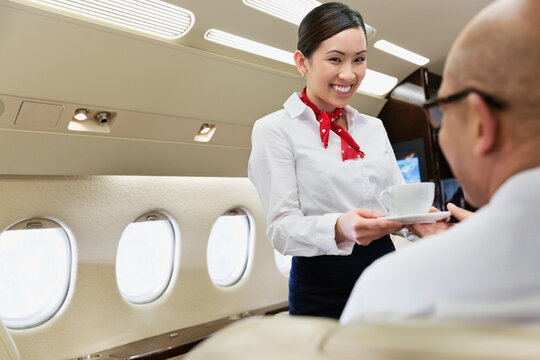 Flight Attendant Serving Coffee To Businessman In Private Jet