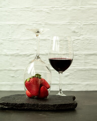 Ripe juicy red beautiful strawberry close-up is an appetizing fresh snack paired with glass of red wine