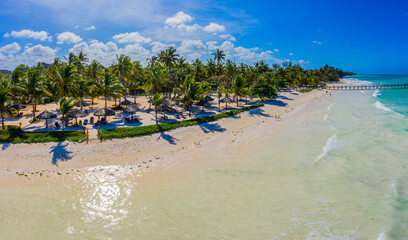 Aerial view of beautiful hotel in Indian ocean at sunset in summer. Zanzibar, Africa. Top view. Landscape with wooden hotel on the sea, azure water, sandy beach, green trees, boat. Luxury resort