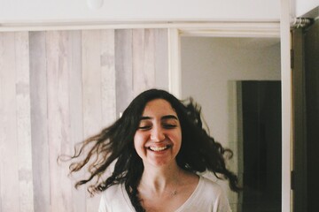 Fototapeta premium Portrait of happy smiling young woman with long hair in fast motion indoors at home 