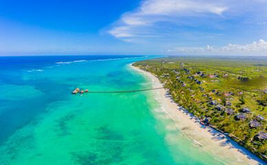 Obraz premium Aerial shot of the Stilt hut with palm thatch roof washed with turquoise Indian ocean waves on the white sand sandbank beach on Zanzibar island, Tanzania.