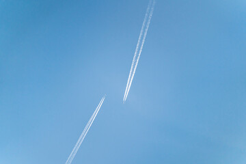 Two aircrafts approach each other in the clear, blue sky.