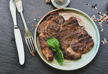 Grilled juicy pork steak, BBQ dishes on black background with copy space. Top view, flat lay food