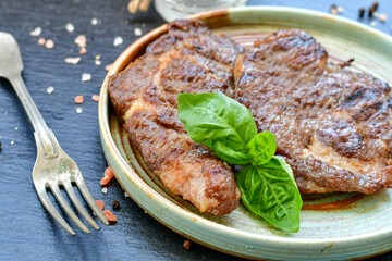 Grilled juicy pork steak, BBQ dishes on black background with copy space. Top view, flat lay food