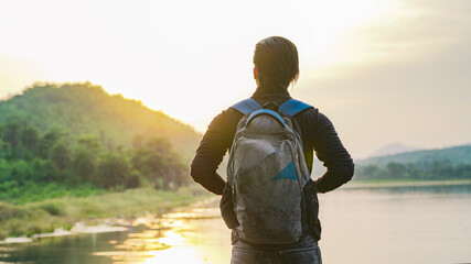 Young man standing near the lake and mountain and enjoying the view of nature