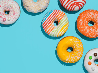 Delicious glazed donuts on blue background. Flat lay - set of different colorful donuts or...