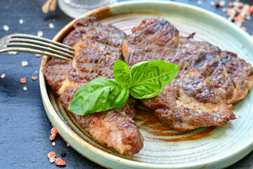 Grilled juicy pork steak, BBQ dishes on black background with copy space. Top view, flat lay food