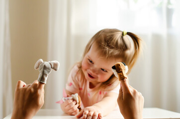 Little expressive girl and his brother playing theater with animal finger puppets. Role-playing...