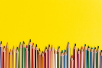 Colouring pencils isolated on yellow background close up concept with copy space for text 