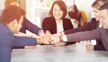 Unity and teamwork concept of young business people folding their hands together