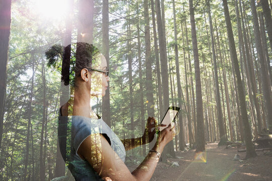 Digital Composite Businesswoman Using Cell Phone In Woods