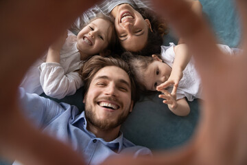 Close up top view portrait of smiling young Caucasian family with two small daughters make...