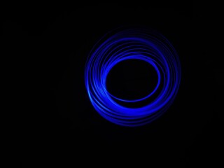Closeup of Neon blue Spirograph geometric pattern abstract isolated in a Black background. Made using light Painting technique, long exposure. Pendulum pattern. Light trails. Waves. Rays. Chakra.