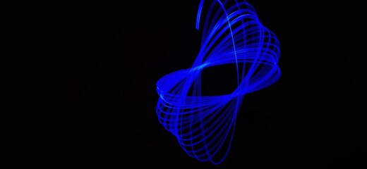 Closeup of Neon blue Spirograph geometric pattern abstract isolated in a Black background. Made using light Painting technique, long exposure. Pendulum pattern. Light trails. Waves. Rays. Chakra.