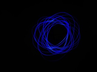 Closeup of Neon blue Spirograph geometric pattern abstract isolated in a Black background. Made using light Painting technique, long exposure. Pendulum pattern. Light trails. Waves. Rays. Chakra.