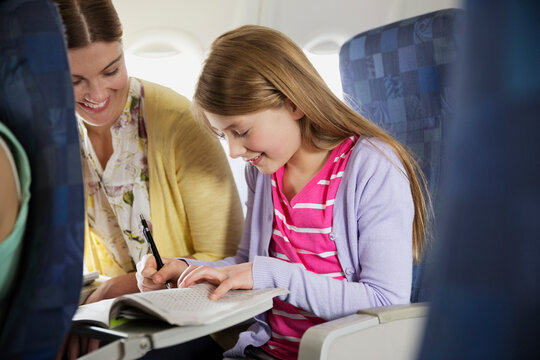 Woman With Daughter Doing Crossword Puzzle In Airplane