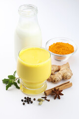 Golden Milk, made with turmeric and other spices,Indian Masala Haldi Doodh. Golden Cinnamon Turmeric Milk. Trendy hot healthy drink with turmeric roots, ginger and spices on a tray