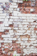 Vertical background with red brick wall with peeling plaster