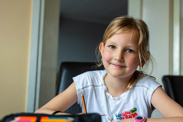 Pensive small cute Caucasian 8s girl sit at desk at home do homework alone write in notebook thinking. Small thoughtful focused little child study learn distant, prepare for school. Education concept.