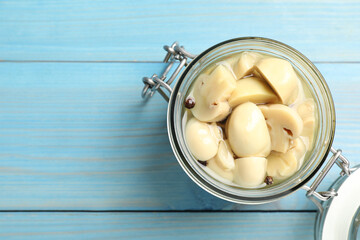 Delicious marinated mushrooms in glass jar on light blue wooden table, top view