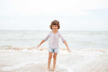 Fototapeta na wymiar Five years cute curlyFive years cute curly caucasian girl painting on sand on the beach. 