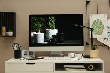 Stylish workplace with computer on white desk near beige wall. Interior design