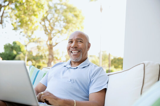 Happy senior man with laptop looking up