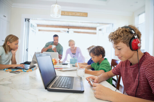 Family Using Laptops, Digital Tablets And Mobile Phone At Table